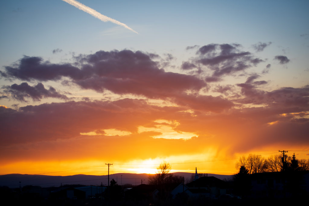 Sunset with colorful clouds and telephone poles in the distance.